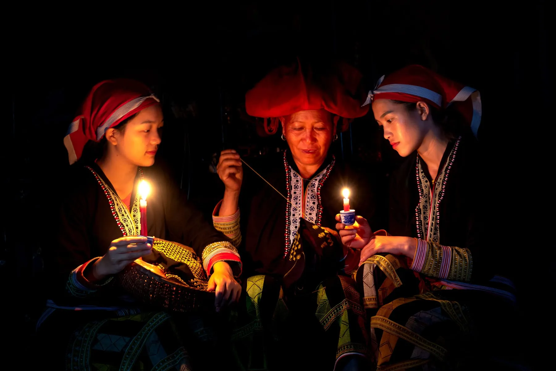 Tres dones amb vestits tradicionals sostenint espelmes enceses