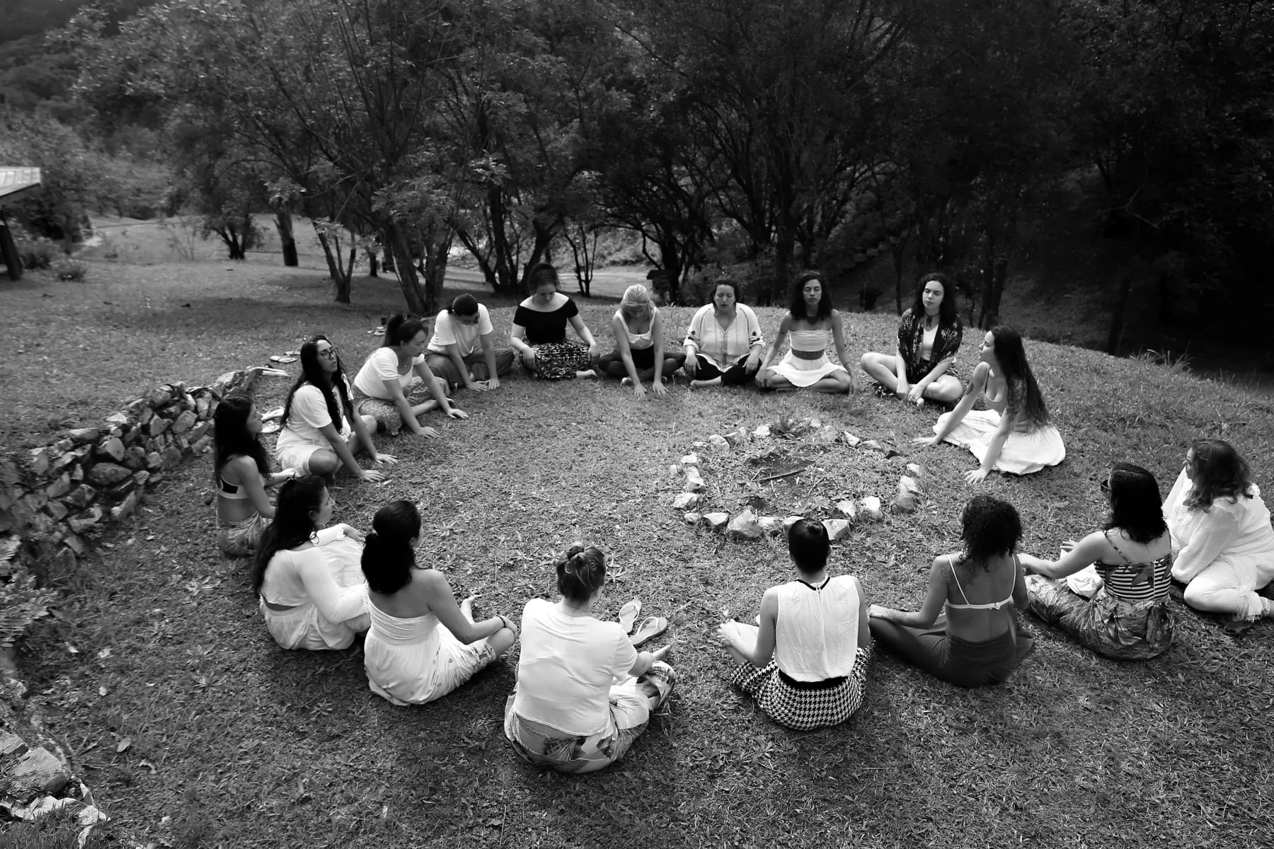Cercle ampli de dones assegudes a terra en un clar del bosc