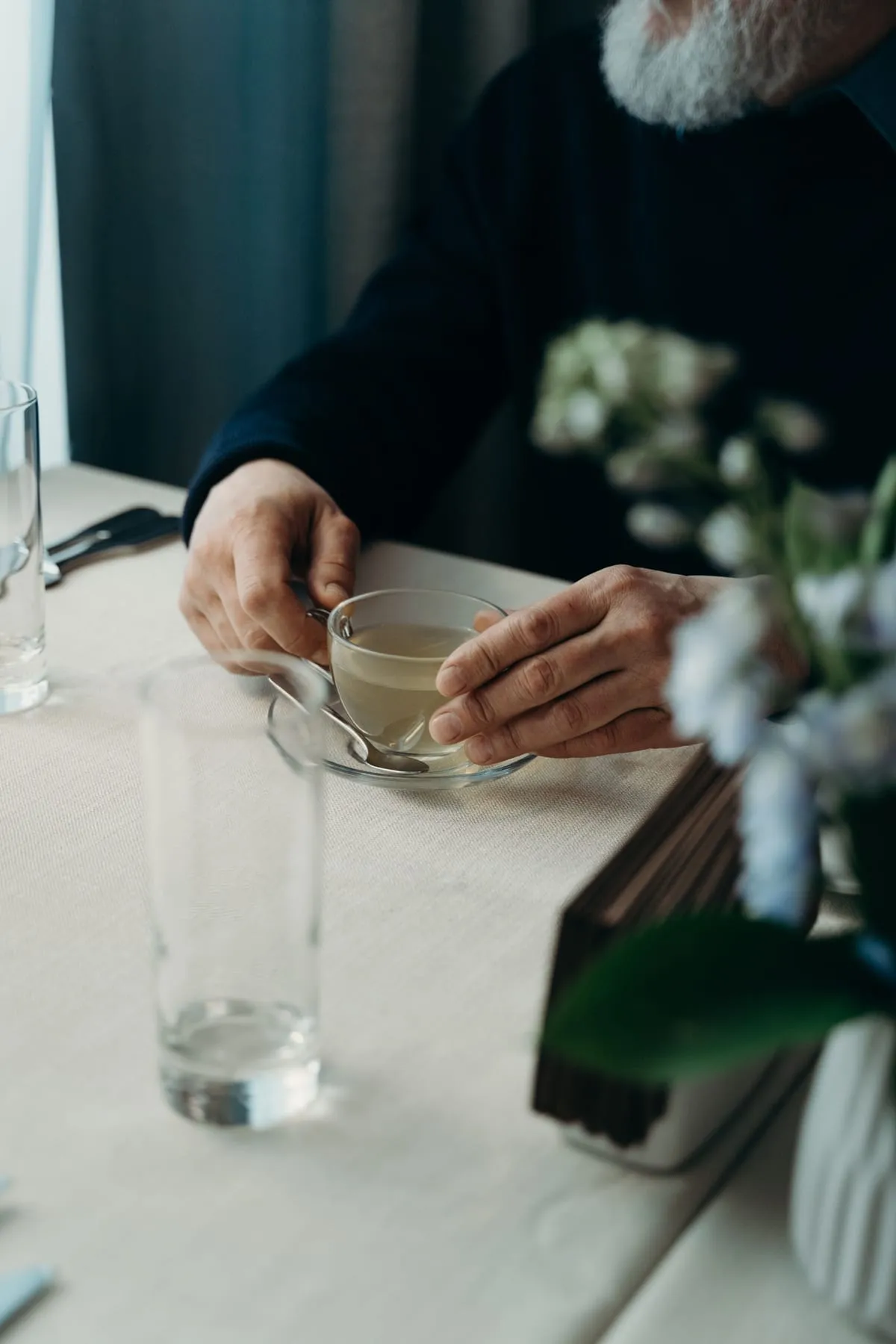 Home gran prenent una infusió assegut a la taula de casa