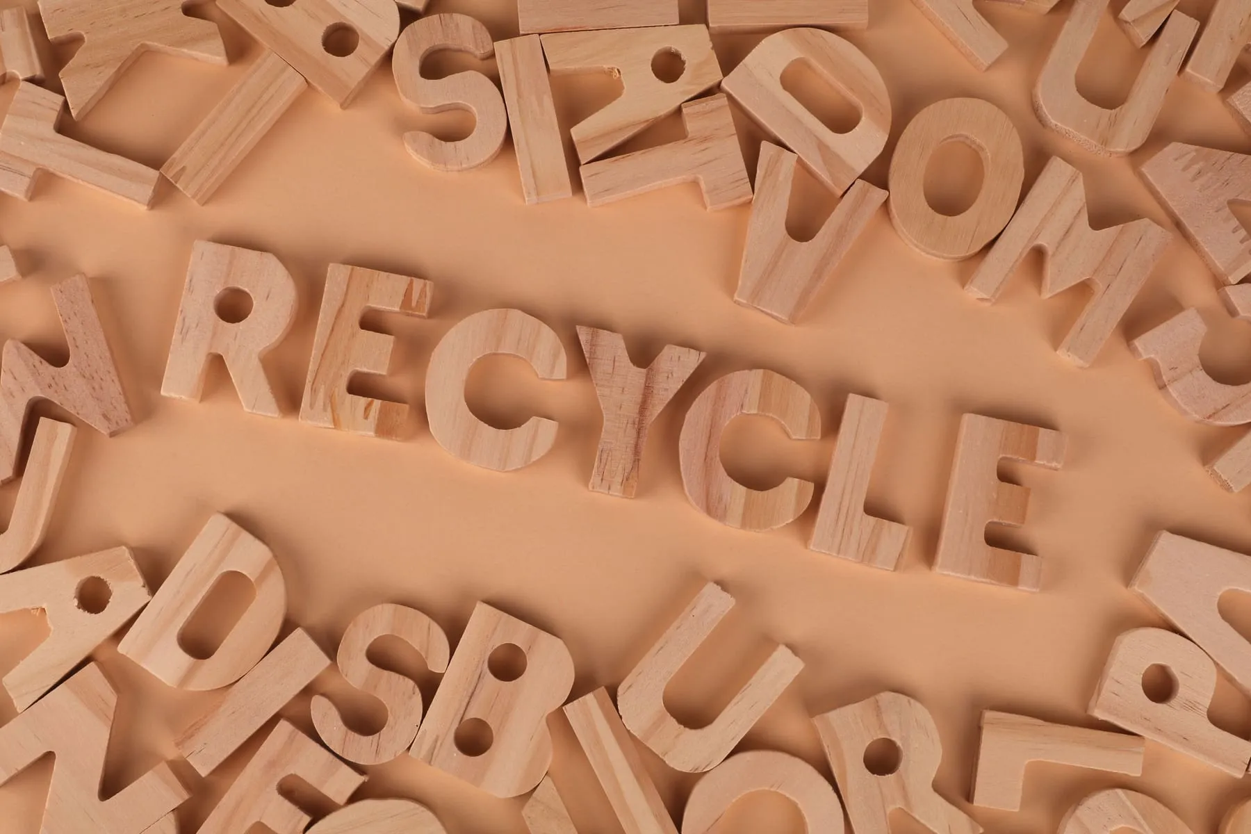 Lletres de fusta que formen la paraula «recycle» entre altres lletres escampades